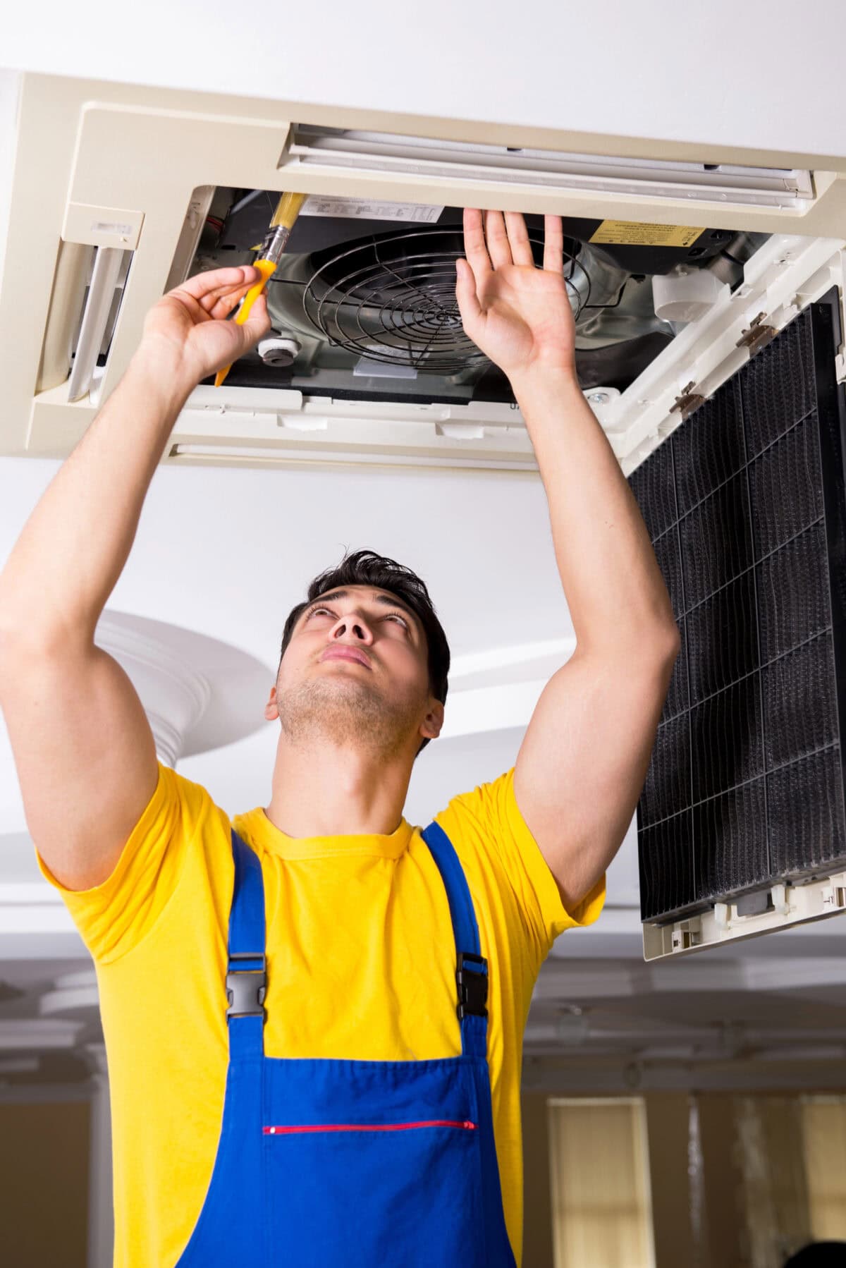 Repairman repairing ceiling air conditioning unit